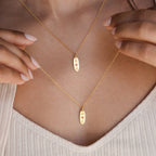 Someone wearing the Newsletter Oval Tag Necklace, a personalized accessory that adds a unique touch to their style.