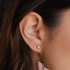 Close-up of a woman's ear wearing Mushroom Studs, gold earrings inspired by nature with colorful accents and sparkling CZ diamonds.