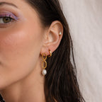 A close-up of a woman's ear adorned with elegant Pearl Drop Link Studs.