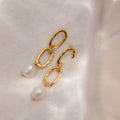 Pearl Drop Link Studs—gold chain link earrings with dangling white pearls, shown on a soft, light fabric background. Elegant pearl drop earrings for a subtle statement.