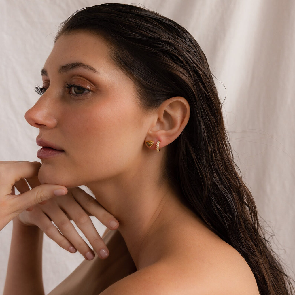 Woman with wet dark hair wearing Seagrass Peridot Marquise Studs, posing with her hand near her chin against a neutral background.