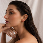 Woman with wet dark hair wearing Seagrass Peridot Marquise Studs, posing with her hand near her chin against a neutral background.
