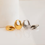 Two pairs of Katrina Ribbed Hoops—one gold, one silver—showcasing a modern chunky ribbed design are beautifully displayed on a white surface.