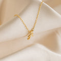 The Grace Dainty Initial Necklace features a custom cursive initial pendant on a gold chain, elegantly displayed on soft, cream-colored fabric.