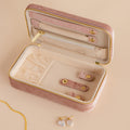 Rectangle Velvet Jewelry Case in pink shown open on a beige surface, displaying earrings, a necklace, and featuring a visible gold zipper detail.