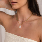 Woman wearing a white off-shoulder top, styled with Boho Beaded Necklaces—gold chains and a pearl pendant add the perfect finishing touch to trendy summer outfits.