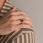 A hand wearing the Vintage Black Signet Ring rests on a shoulder, both dressed in beige and navy striped shirts.
