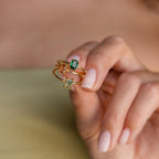 A hand holds three Emerald Cut Solitaire Rings, each set with a rectangular green, yellow, or peach gemstone—ideal as elegant birthstone rings or striking statement pieces.