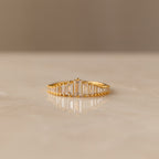 The Art Deco Diamond Earrings & Ring Set in 18K Gold features a gold ring with vertical rectangular stones in a gradual height pattern, evoking vintage elegance, displayed beautifully on marble.