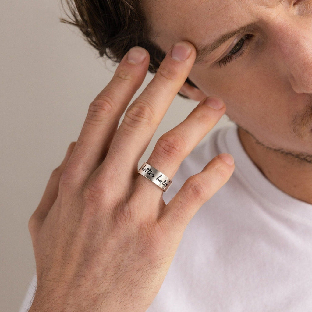 A man wearing a Thick Handwriting Band, a silver engraved statement ring on his middle finger, touching his face.