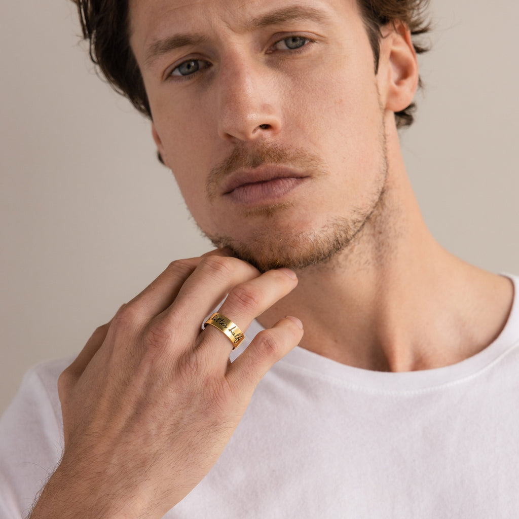 Man with short brown hair wears a white shirt and the Thick Handwriting Band statement ring, looking seriously at the camera.