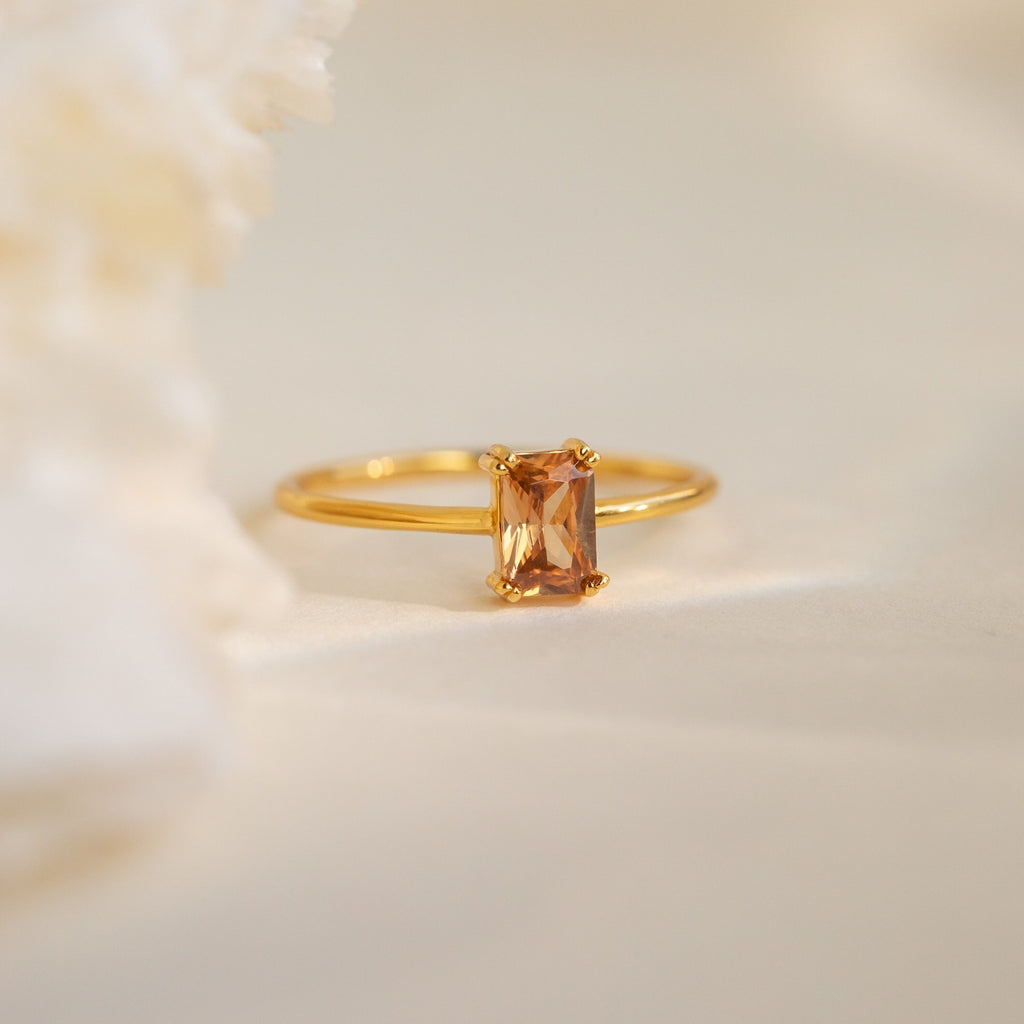 The Citrine Emerald Ring features an emerald-cut peach gemstone on a soft, neutral background—an elegant choice for a November birthstone or as a stylish Citrine Birthstone Ring.
