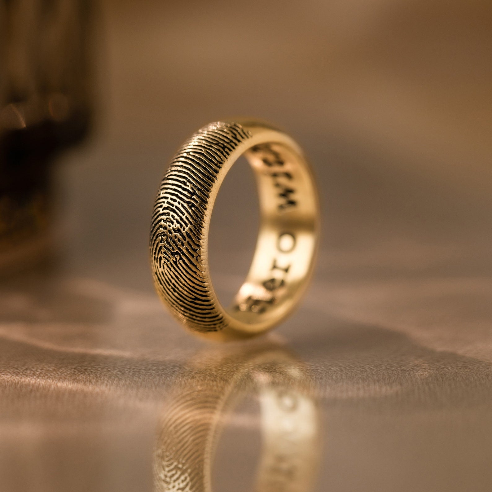 The Thick Half Round Fingerprint Ring features a gold minimalist band with a unique fingerprint design engraved on its outer surface—an ideal choice for those seeking personalized jewelry.
