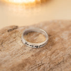The Handwriting Band features your custom inscription on wood with a silver accent—ideal as a heartfelt Christmas gift, beautifully highlighted by blurred warm lights in the background.