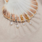 The Pearl Drop Link Studs are elegantly displayed on a seashell.
