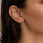A close-up of a woman's ear adorned with Seagrass Peridot Marquise Studs.