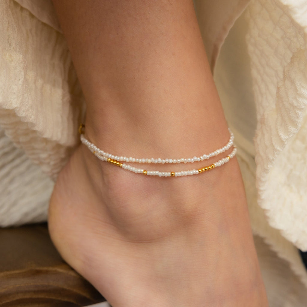 A close-up of an ankle adorned with the Dainty Pearl Beaded Anklet, showcasing delicate pearls and gold accents for an elegant, refined look.