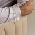 A man’s arm rests on a chair, his white shirt accessorized with Engraved Cufflinks—gold, personalized, and etched with “MMK.”.