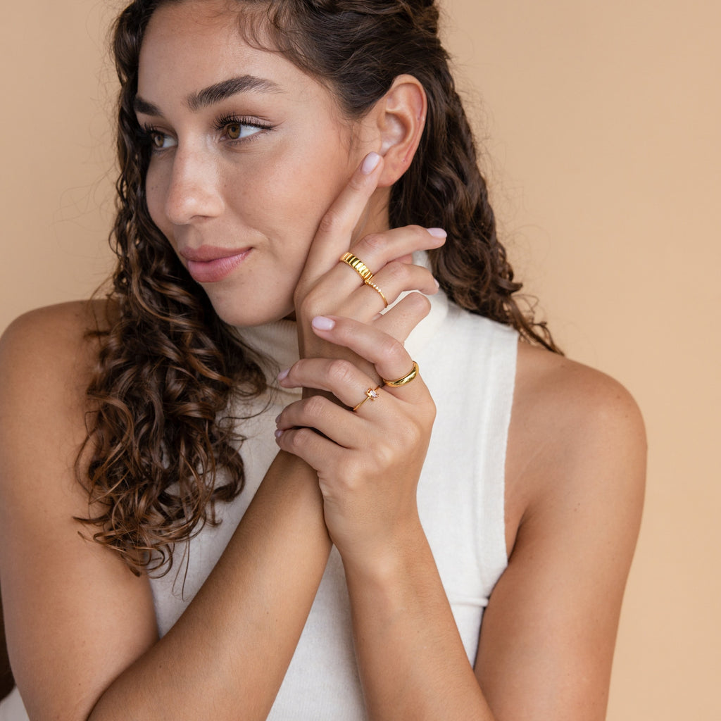 A woman with curly hair in a white sleeveless shirt showcases the elegant Citrine Emerald Ring, an ideal choice for anyone who cherishes the November birthstone.