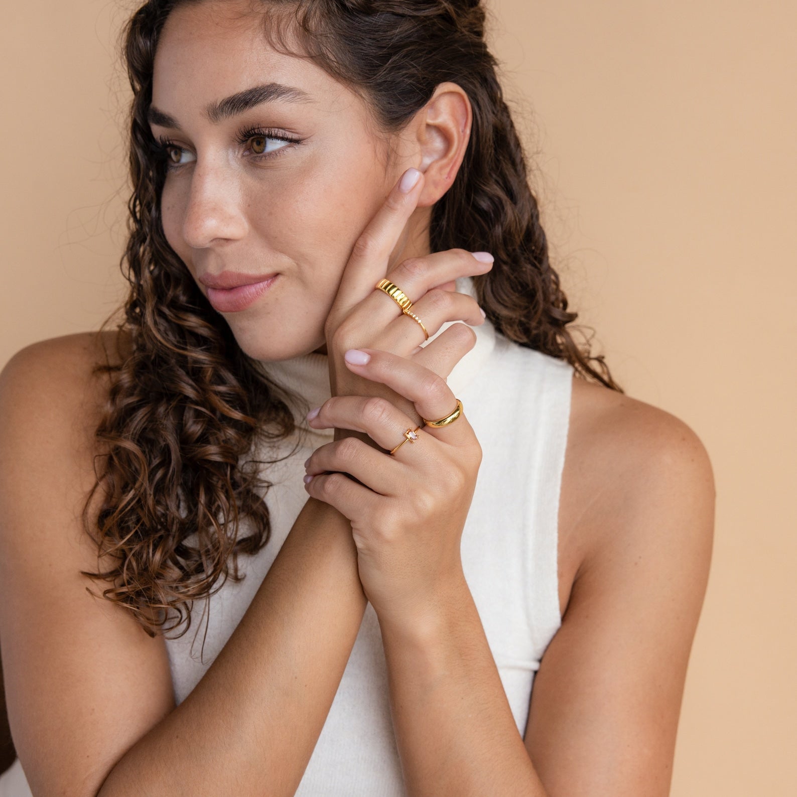 A woman with curly hair in a white sleeveless shirt showcases the elegant Citrine Emerald Ring, an ideal choice for anyone who cherishes the November birthstone.