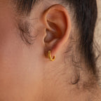 Close-up of a person's ear wearing Ribbed Huggies—small, ribbed hoop earrings perfect for those who love dainty earrings with subtle texture.
