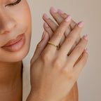 A woman with soft pink nails showcases a stacking gold ring with a small green stone and elegantly pairs it with the Thin Name Signet Ring.