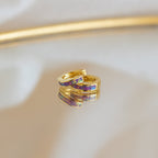 Lavender Opal Inlay Huggies with purple and red accents, featuring a subtle opal shimmer, rest elegantly on a reflective surface.