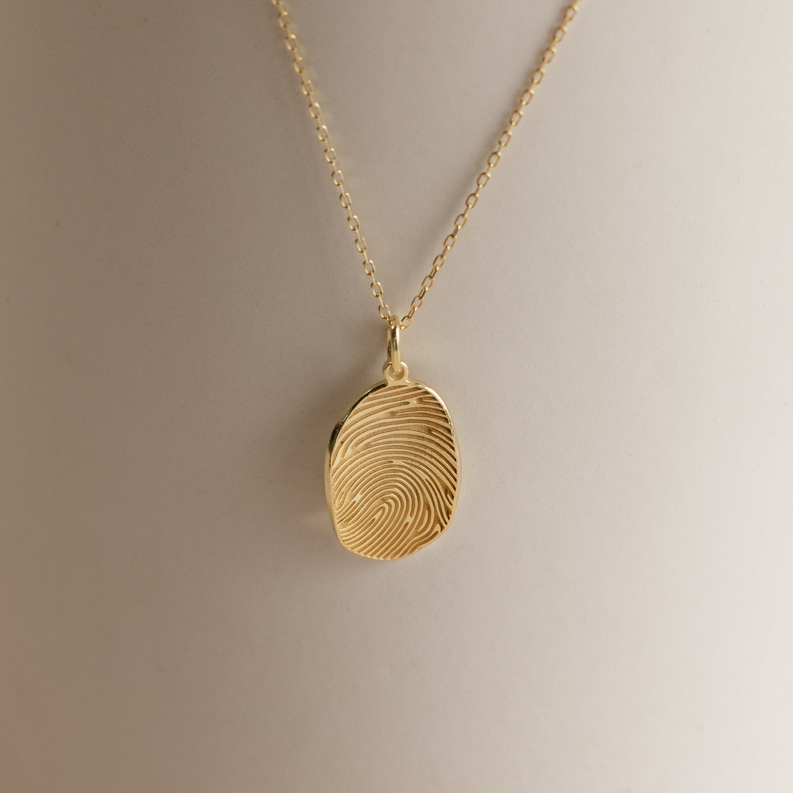 Custom Fingerprint Necklace in Rose Gold featuring an oval pendant engraved with a unique fingerprint, shown on a neutral background—an ideal sentimental gift.