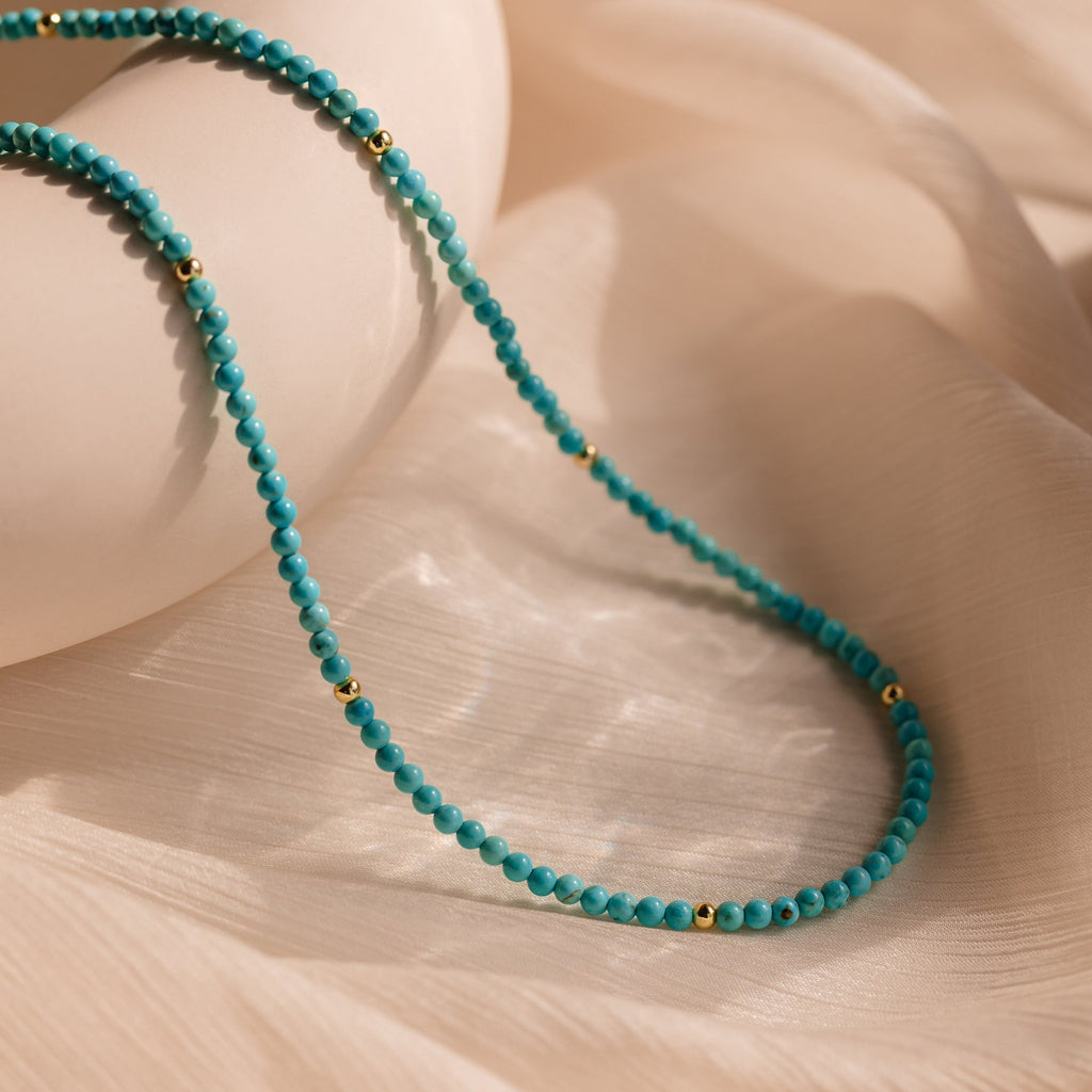 Beaded Belly Chains adorned with turquoise beads and small gold accents exude bohemian elegance, displayed on a soft, beige fabric background.