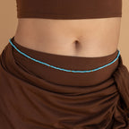 A person wearing a brown crop top and brown sarong enhances their look with Beaded Belly Chains for a stylish boho-chic touch.