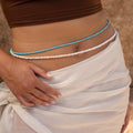 A woman showcases Beaded Belly Chains and a sheer wrap skirt, capturing effortless bohemian elegance with her hand on her hip.