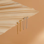 Two pairs of Diamond Chain Earrings Set, one gold and one silver, from the Golden Goddess Collection, displayed on a folded beige textured surface.