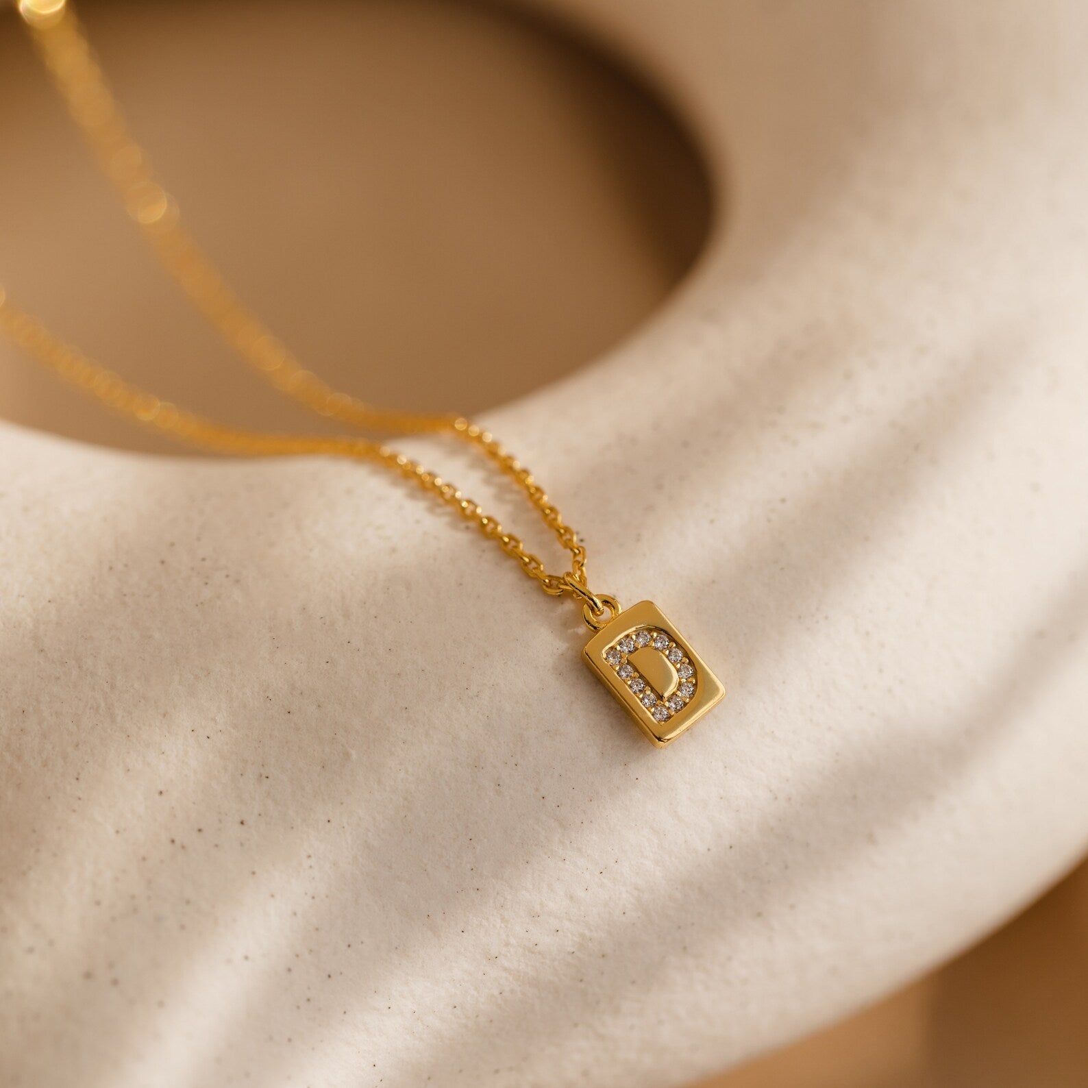 Mini Pave Initial Tag Necklace featuring a rectangular gold pendant with the letter D outlined in sparkling pave stones—a stylish and personalized jewelry piece.