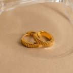 Ribbed Huggies displayed on a beige surface with a clear object in the background, offering the perfect balance of bold style and dainty elegance.