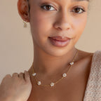 Woman wears the Flower Pearl Station Necklace in Sterling Silver with delicate flower-shaped pearl accents, smiling softly—an ideal choice for a meaningful bridesmaids or Mother’s Day gift.