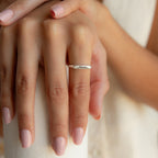 A hand with pale pink nails wears the Paris Thin Name Signet Ring in Sterling Silver engraved with the name Naomi.
