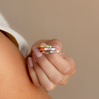 A hand with pink nails holds three Paris Thin Name Signet Rings, each engraved with the names Chloe, Dani, and Kevin.