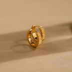 Ribbed Huggies feature a textured, ridged design and rest on a beige surface—ideal for adding bold elegance to any look.