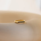 The Thin Fingerprint Signet Ring, engraved with your unique fingerprint, rests on a smooth beige surface in soft natural light—a personalized gift to treasure.