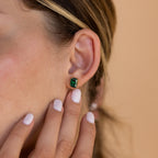 A close-up of a woman's ear adorned with Emerald Birthstone Studs, elegant gemstone earrings that make perfect personalized gifts for any occasion.