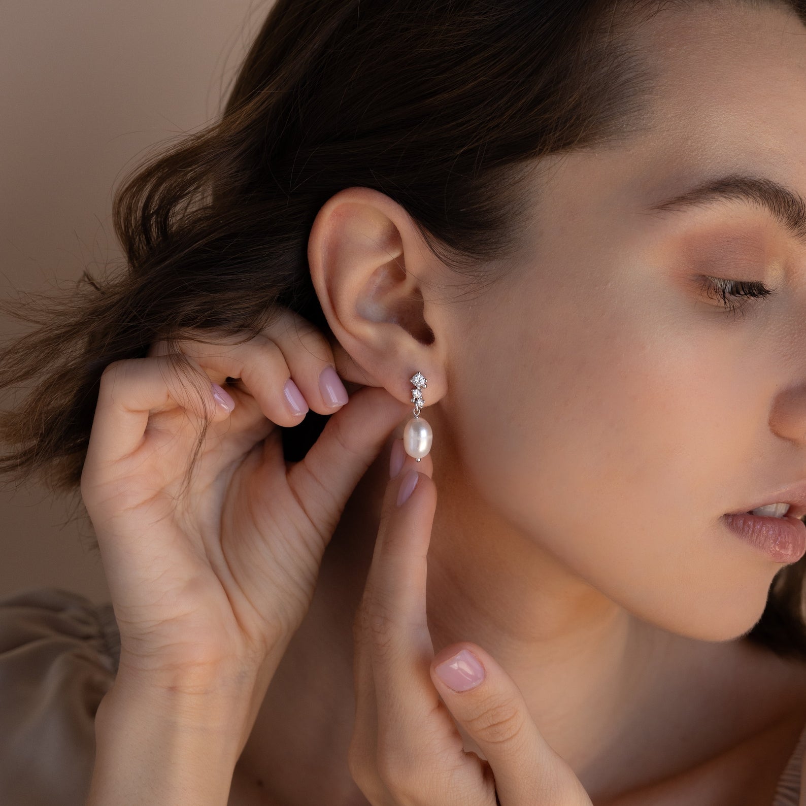 Model adjusting the silver version of the Millie Drop Earrings, highlighting the delicate drop and luster of the pearl.