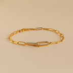 The Pave Link Chain Bracelet features elongated gold links and a crystal-encrusted clasp, making it an eye-catching statement piece, shown here on a beige background.