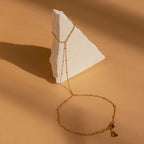 Beaded Hand Chain Bracelet elegantly displayed on a white triangular stone against a beige background—a chic statement piece that enhances any outfit.