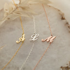 Three Carrie Initial Bracelets, each with A, L, and M letter charms in gold, silver, and rose gold, rest on marble—ideal as personalized jewelry or a custom initial bracelet for everyday style.
