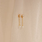 Diamond Pearl Drop Earrings with crescent moons, chain drops, and pearls are displayed on a soft beige fabric background, highlighting their timeless elegance.