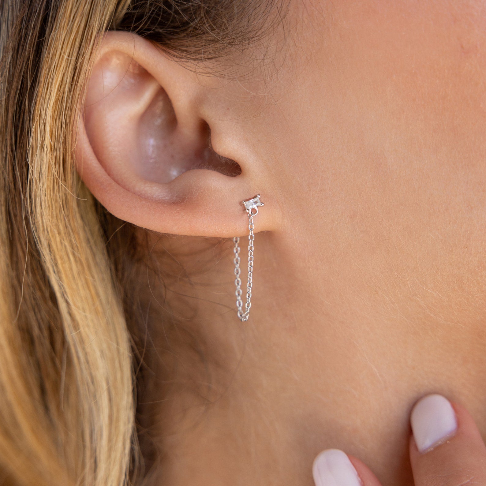 Close-up of a woman's ear wearing Baguette Chain Studs, her hand gently touching her neck and highlighting a chic, minimalist earring stack.