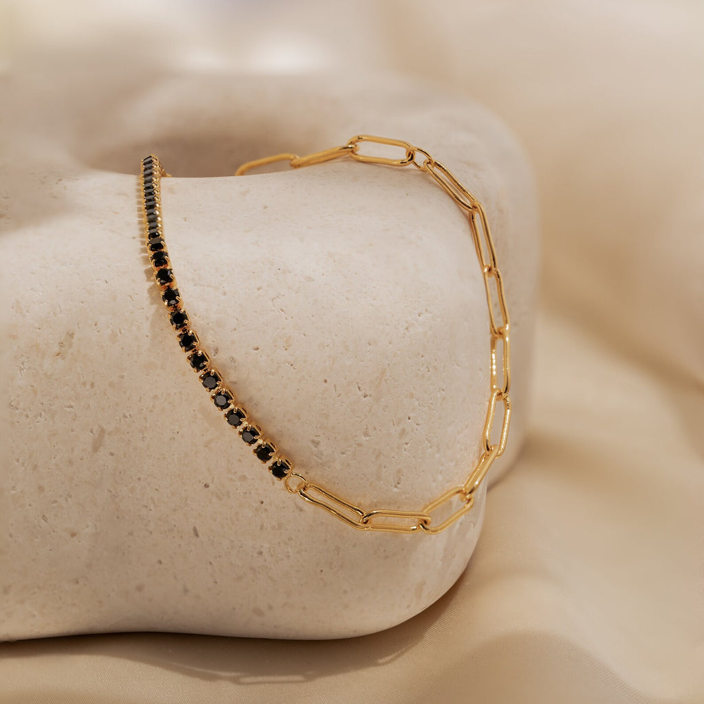 Black Diamond Tennis Bracelet—an eye-catching statement piece featuring black stones, showcased on a smooth beige stone with a soft, neutral backdrop.