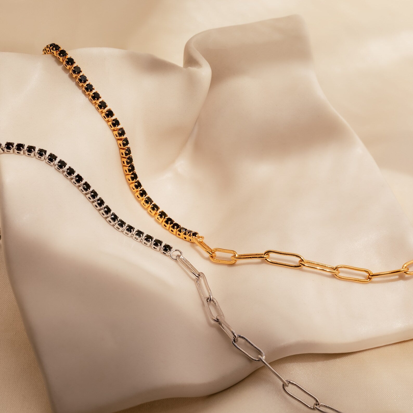 A stunning Black Diamond Tennis Bracelet, perfect as a statement accessory, is displayed on a soft, ivory satin fabric backdrop.