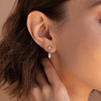 A close-up of a woman's ear wearing Moon & Star Pearl Earrings, showcasing the delicate pearl charm and the sparkling diamond gemstone stud.