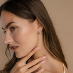 Side portrait of a model with her hand gracefully touching her chin, wearing the silver Aquamarine Diamond Huggies for a minimal yet luminous look.